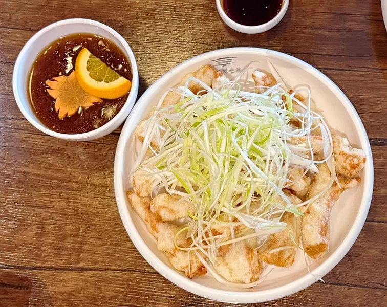A plate of Korean pork tenderloin sweet and sour pork topped with green onion strips