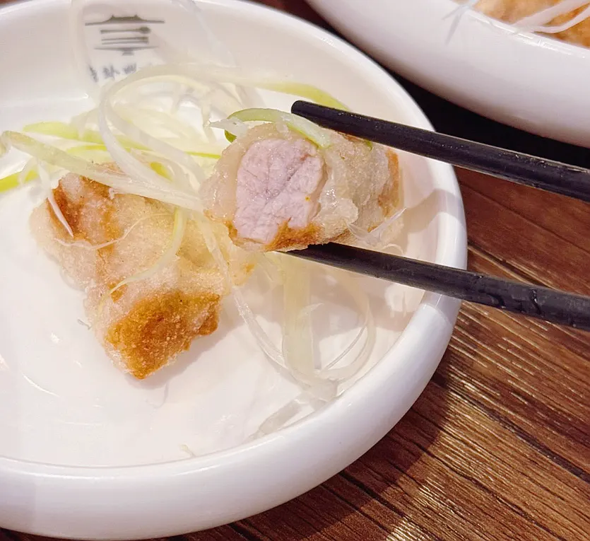 A plate of sweet and sour pork garnished with green onion strips