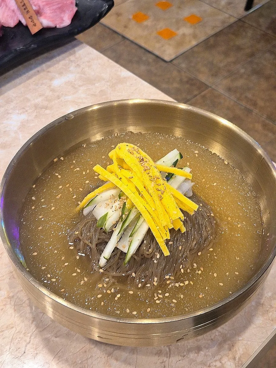 Mul naengmyeon topped with egg strips and cucumber