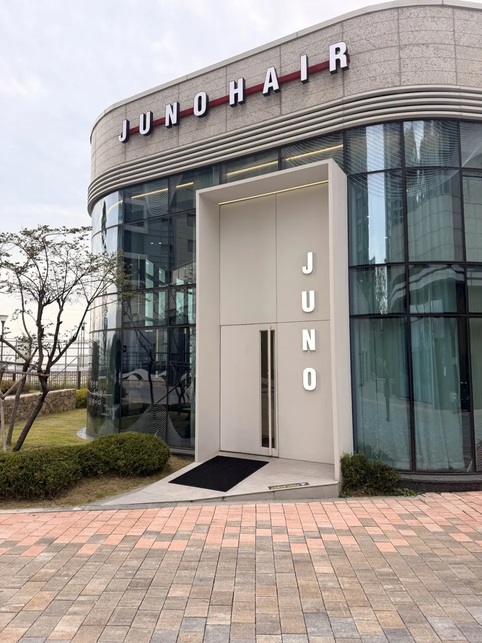 곡선 건물에 걸린 JUNO HAIR 간판과 매장 입구
