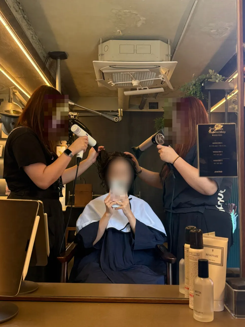 Two staff members blow-drying the hair together at the finishing stage