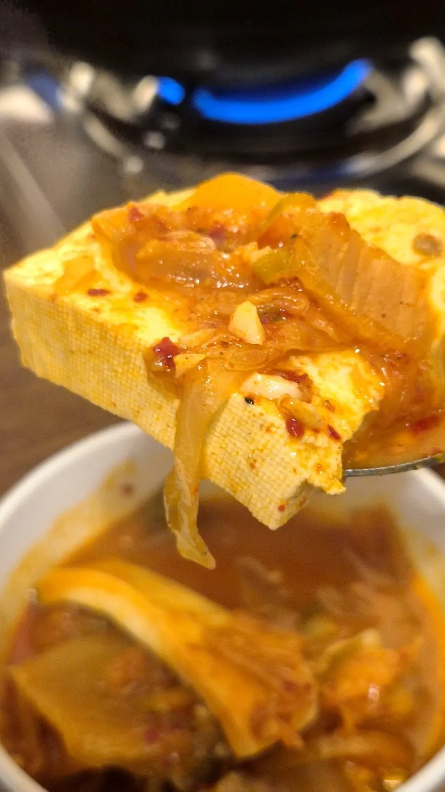 Pot of pork belly kimchi jjigae full of tofu and mushrooms