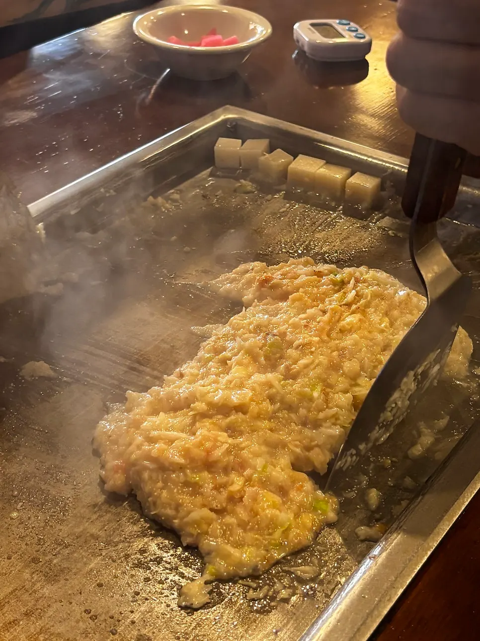 Staff member cooking monjayaki on the teppan