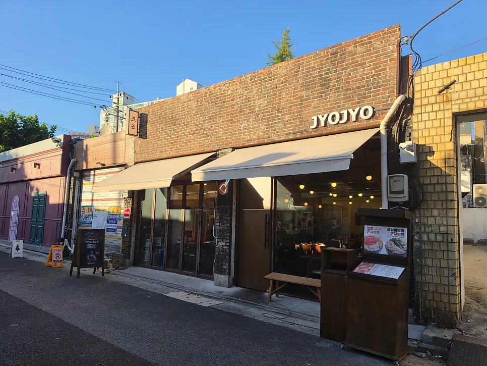 붉은 벽돌 건물 1층 죠죠 문래점 외관과 베이지색 어닝