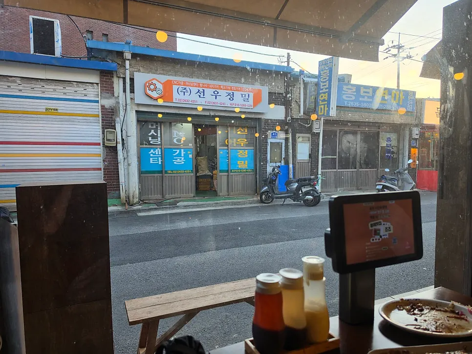 통유리창 너머 철공소 골목이 보이는 창가 자리