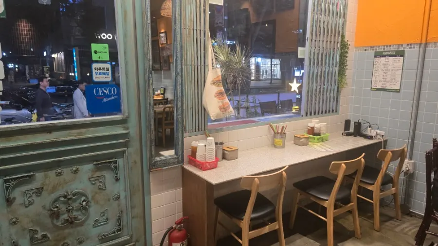 Exterior of Kkamon with mint-colored door and yellow sign