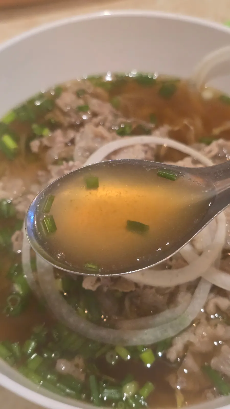 A bowl of Kkamon pho with deeply colored broth