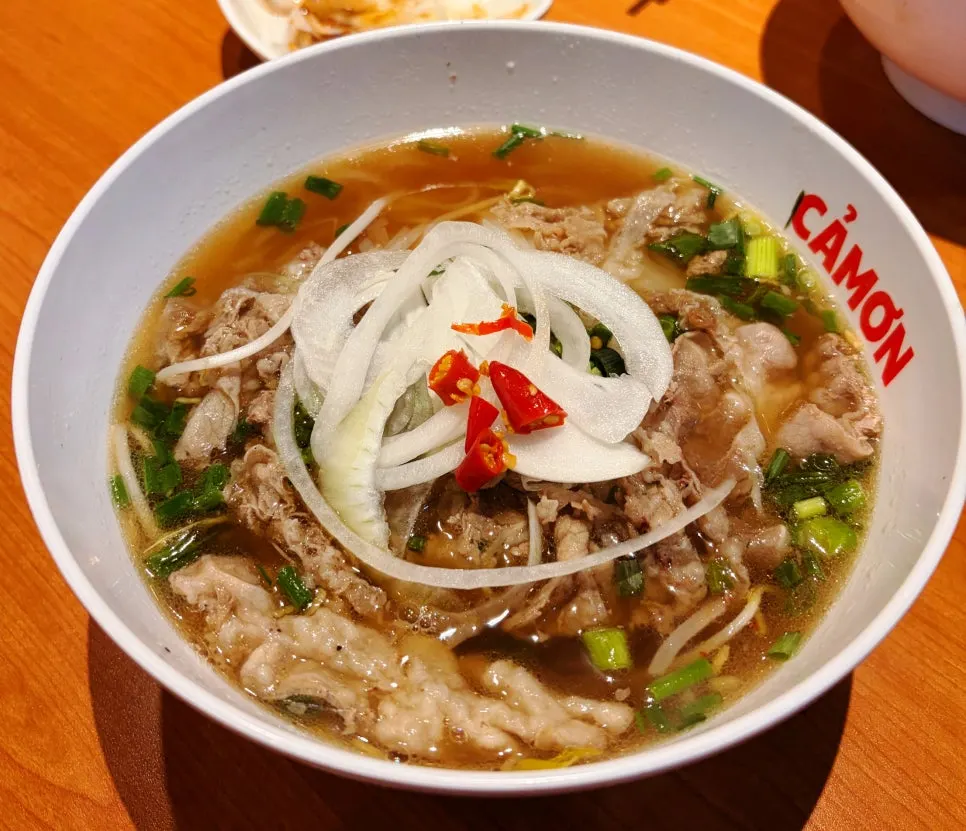Kkamon pho topped with brisket, scallion and onion