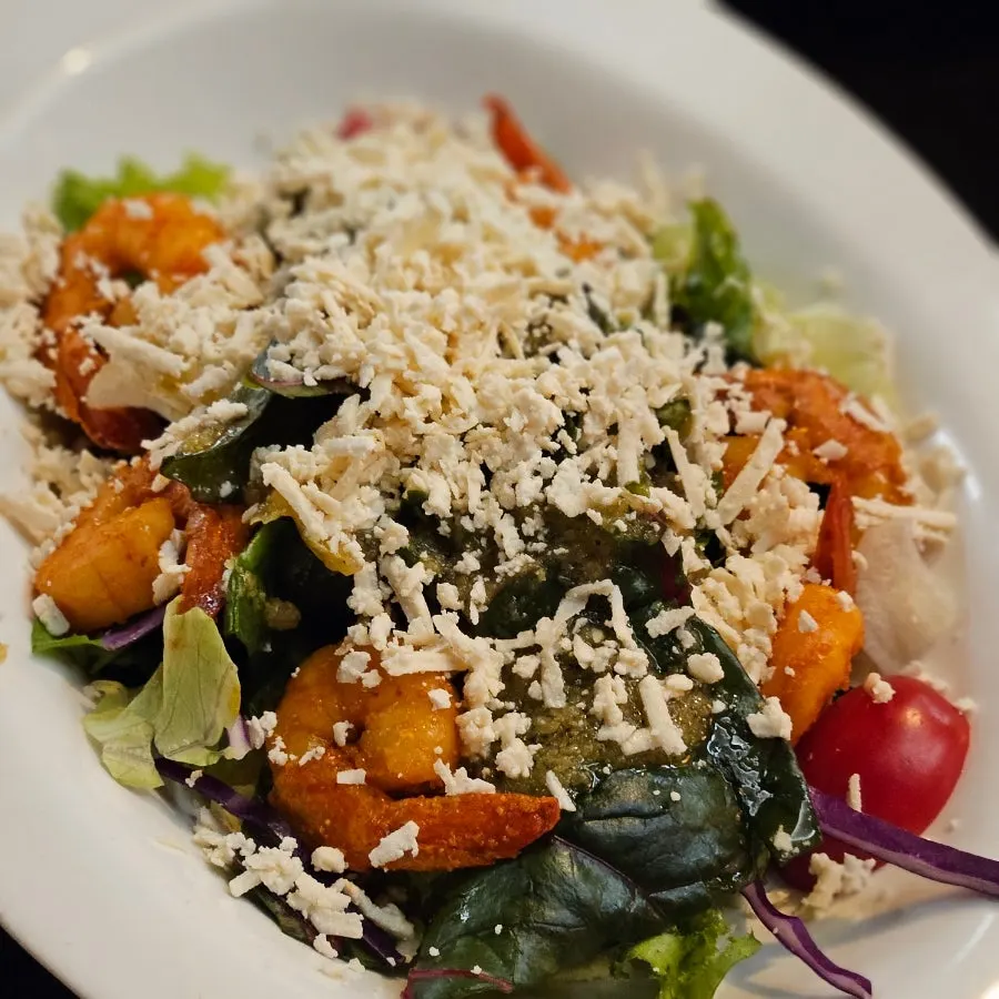 Close-up of shrimp salad topped with Indian-style cheese