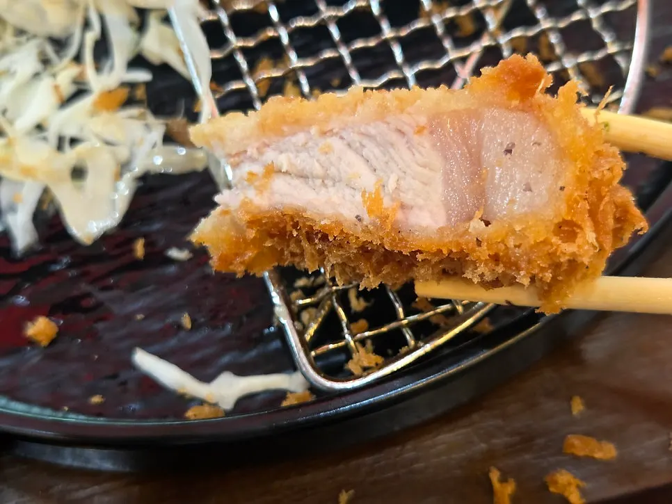 A bite-size piece of pork loin katsu picked up