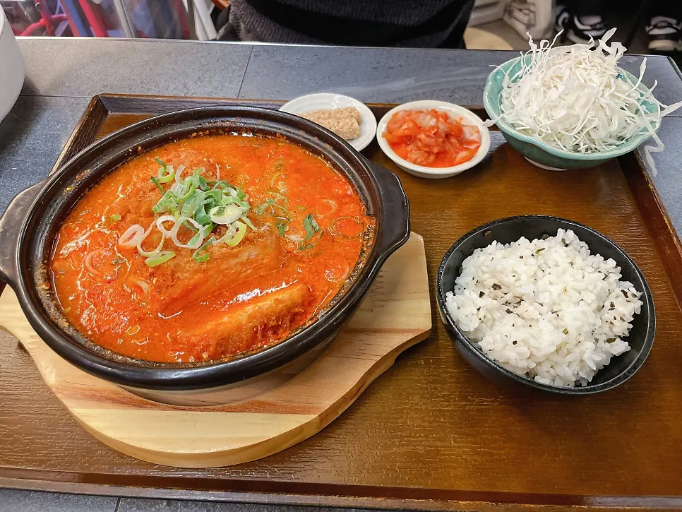 Table setting of kimchi katsu nabe with vivid red broth