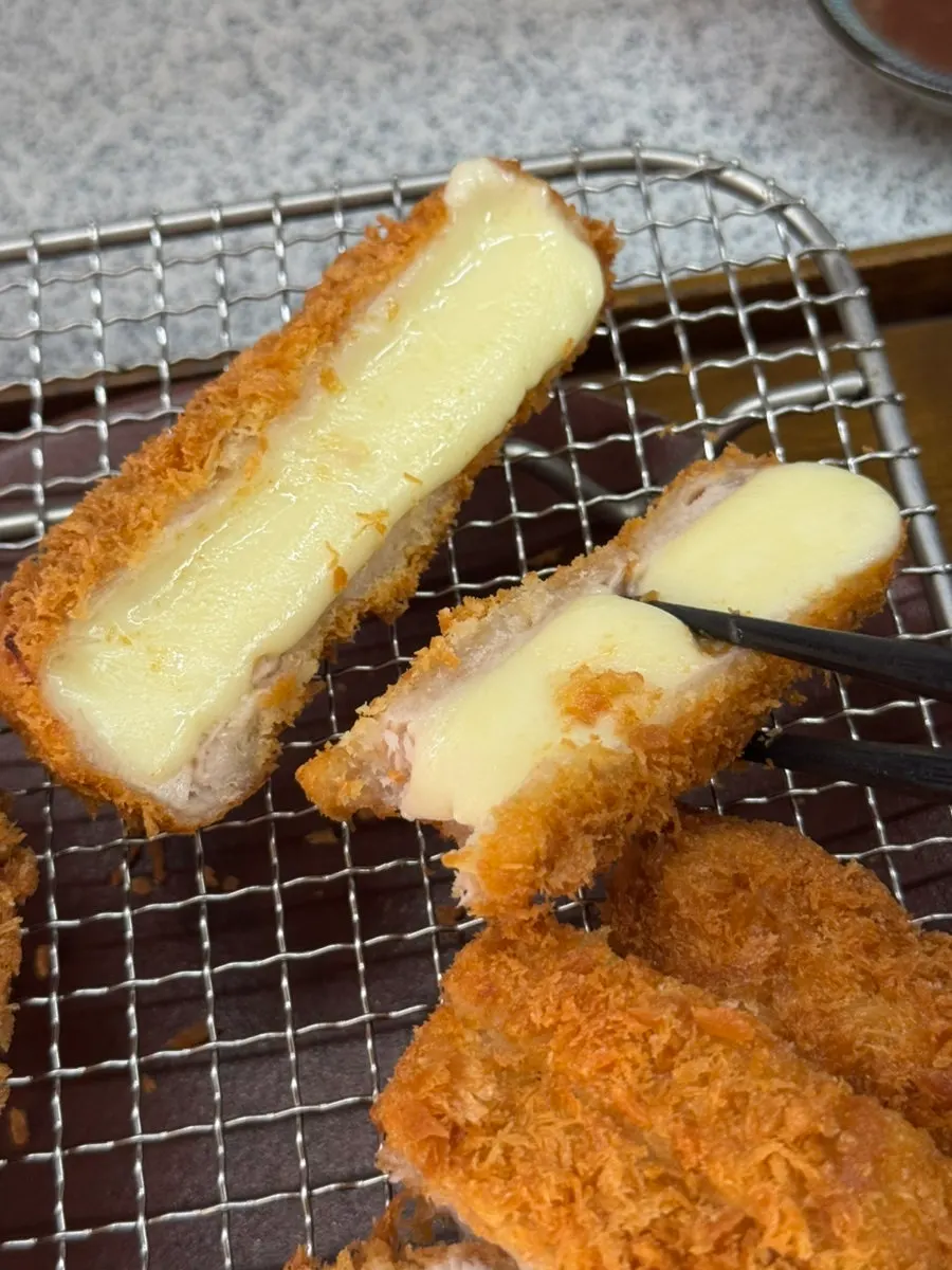 A piece of cheese katsu with melted cheese stretching