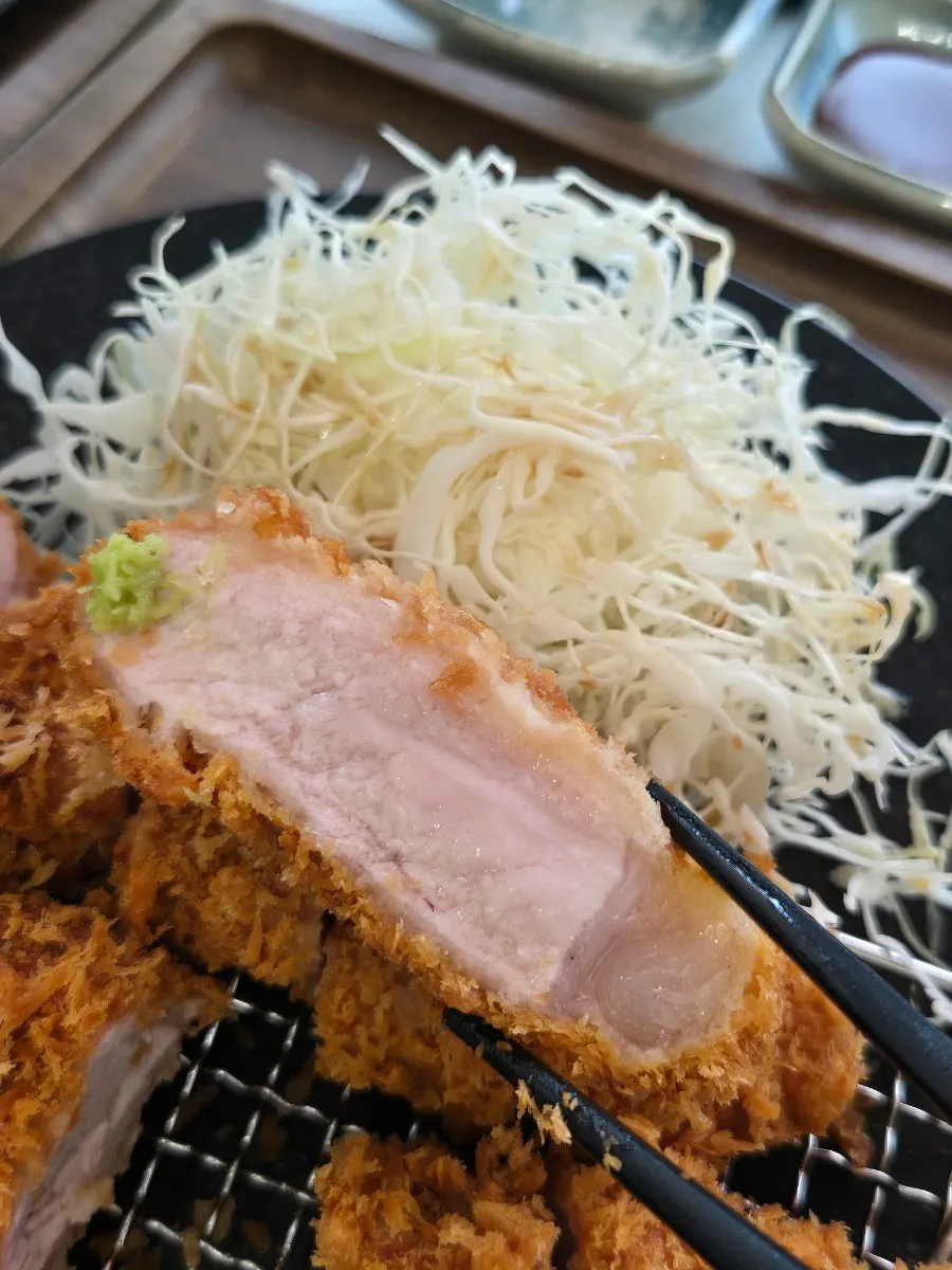젓가락으로 집어 올린 두꺼운 등심 돈카츠 한 조각
