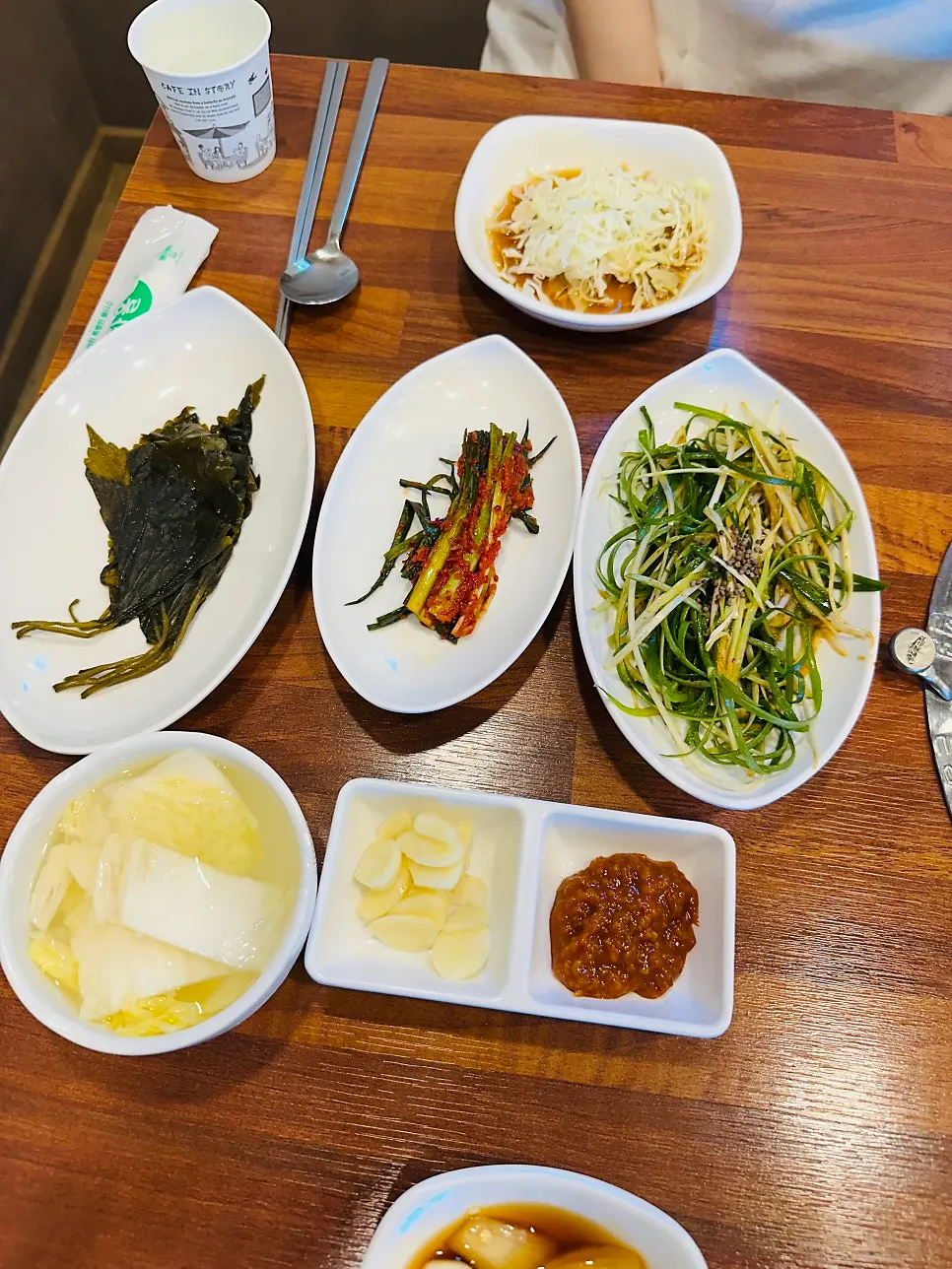 Side dish spread including pickled perilla leaves and scallion kimchi