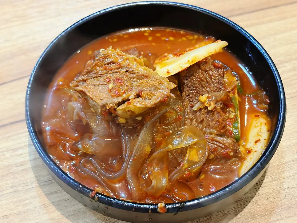 Flat glass noodles and rice cake scooped onto a personal plate