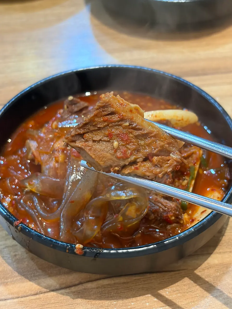 A thick piece of beef rib picked up with chopsticks