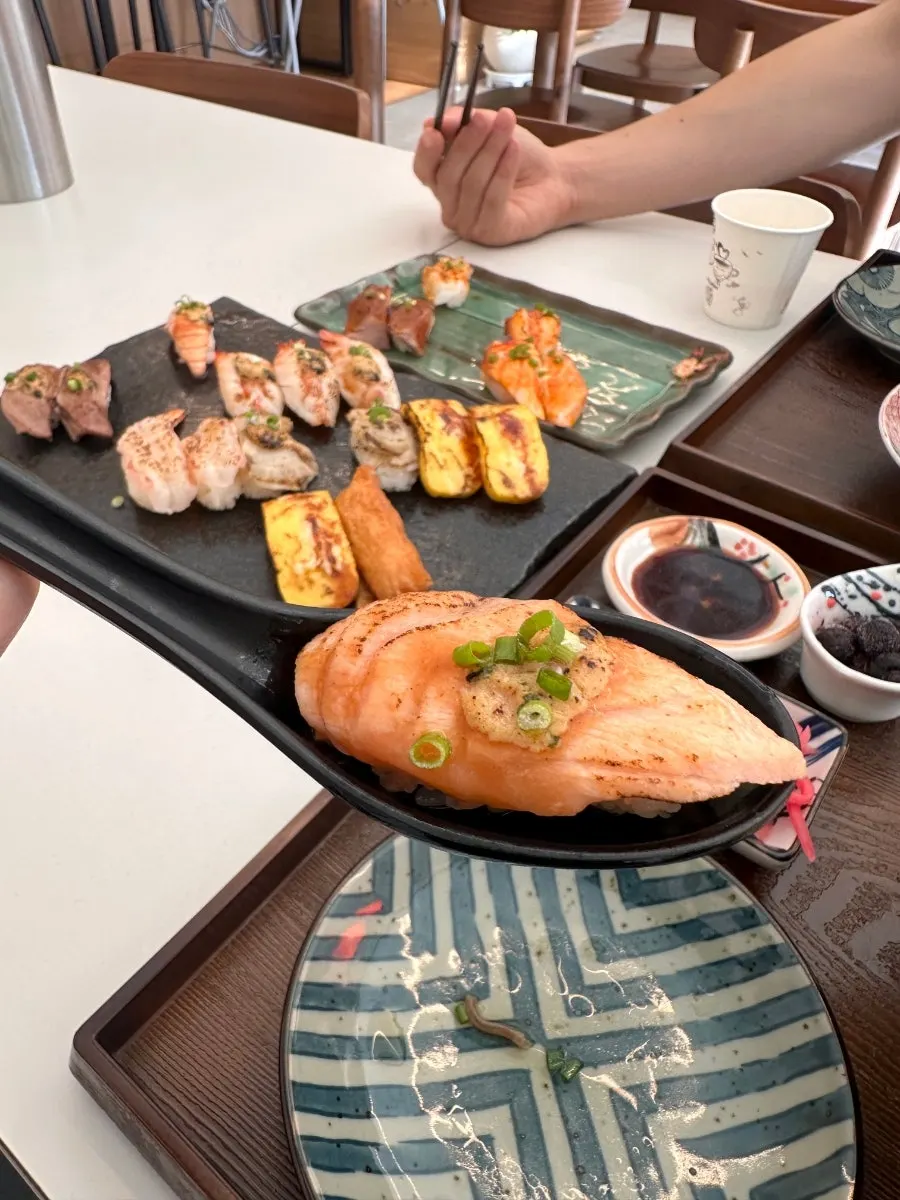 Vertical close-up of a single piece of flame-seared sushi