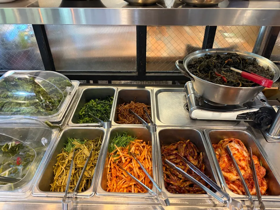 Namul side dishes kept warm on a burner at the self-serve bar