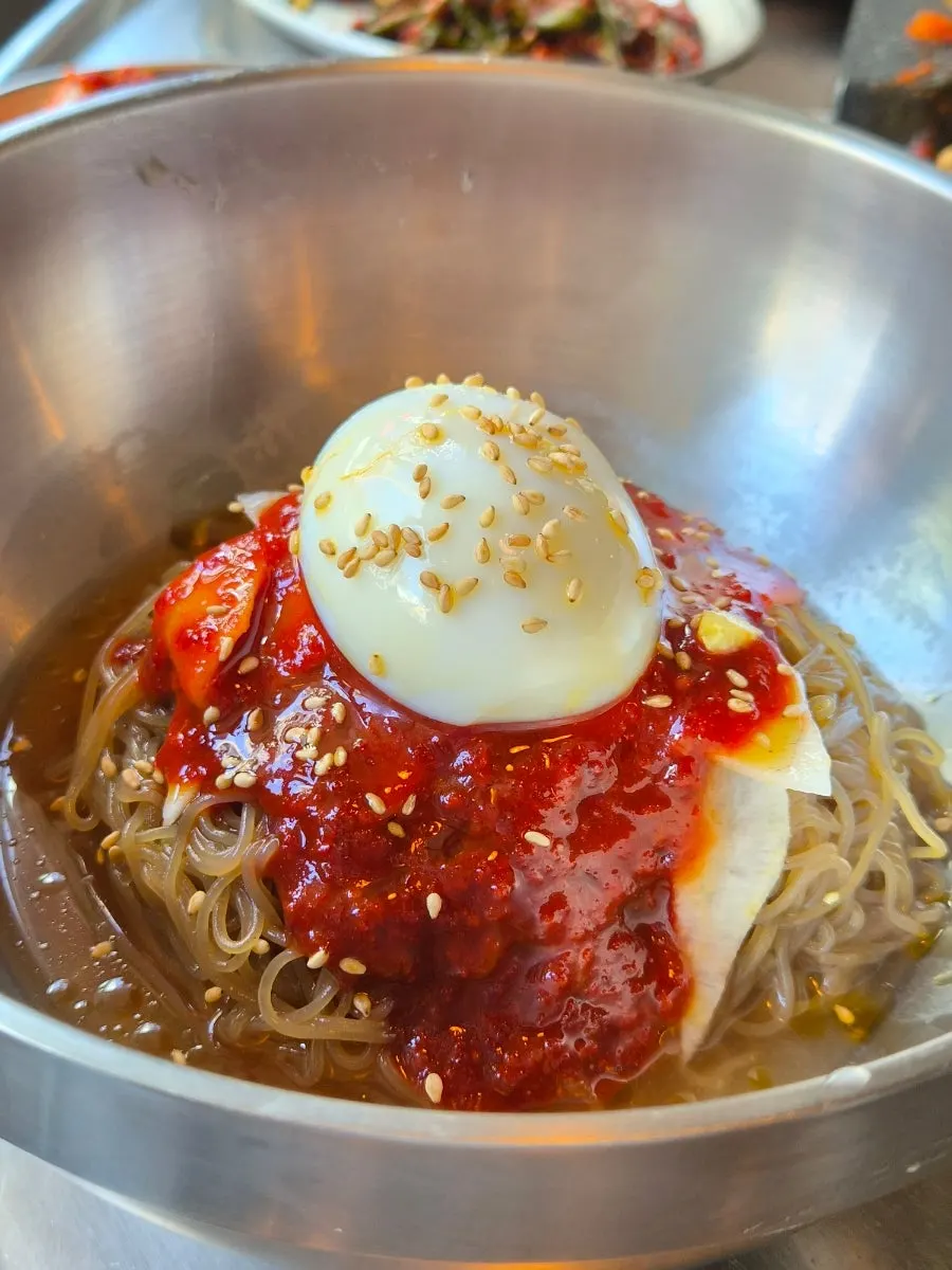 A bite of bibim naengmyeon eaten with meat