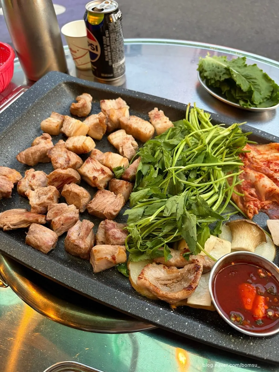 Grilled meat topped with kimchi and minari on the griddle