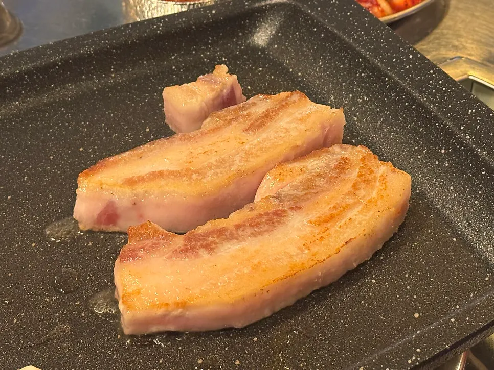 Thick pork belly turning golden brown on the grill