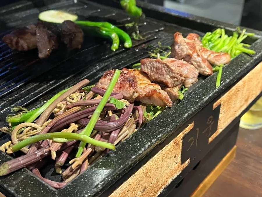 Staff member grilling meat on the table grill