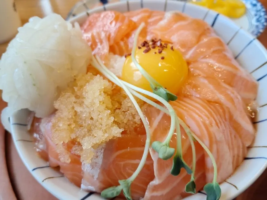 A spoonful of salmon rice bowl topped with wasabi