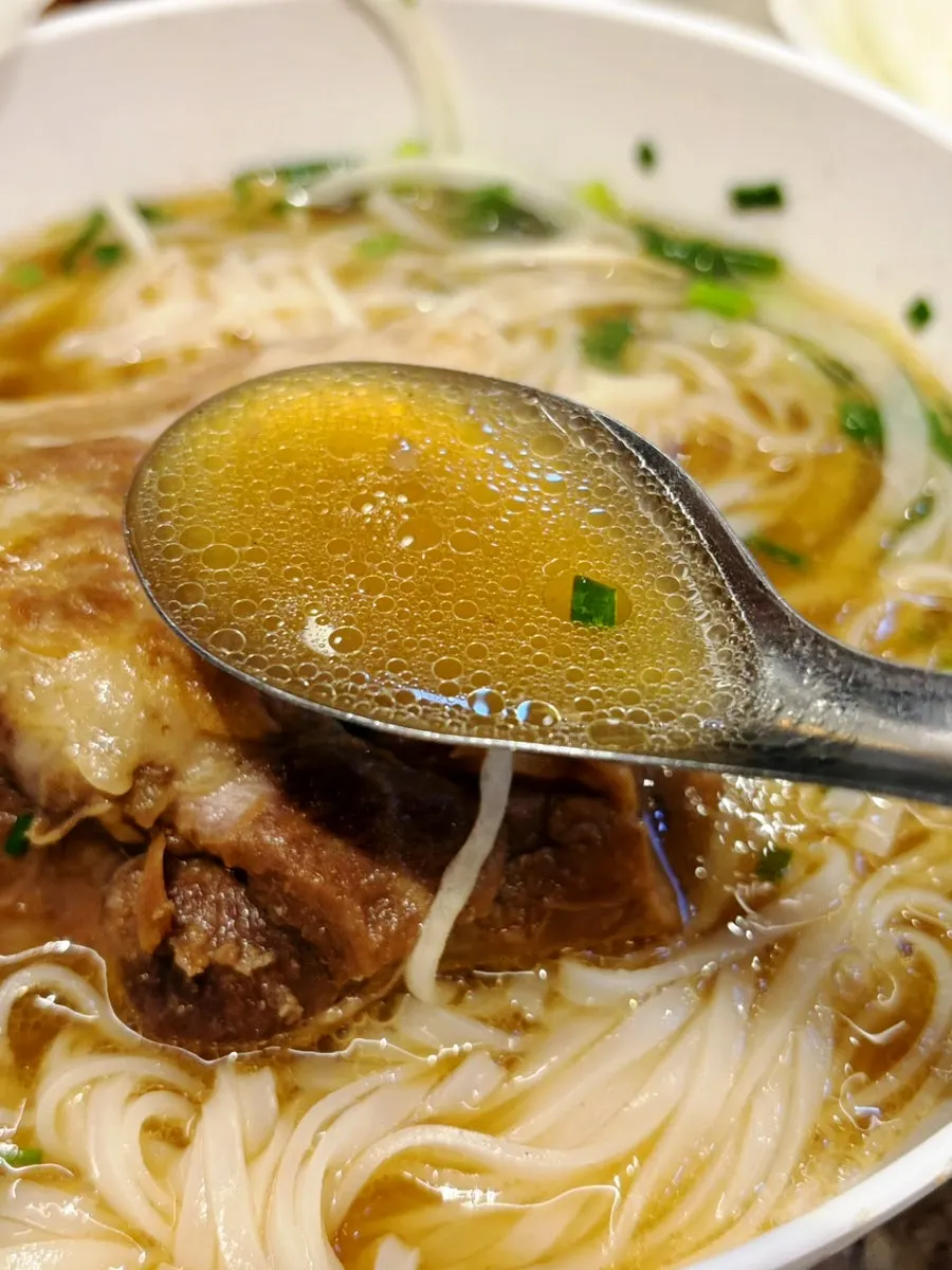 Lifting noodles from the pork backbone pho