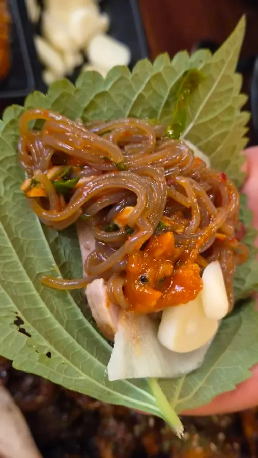Charcoal-grilled jjokbal wrapped in a lettuce leaf
