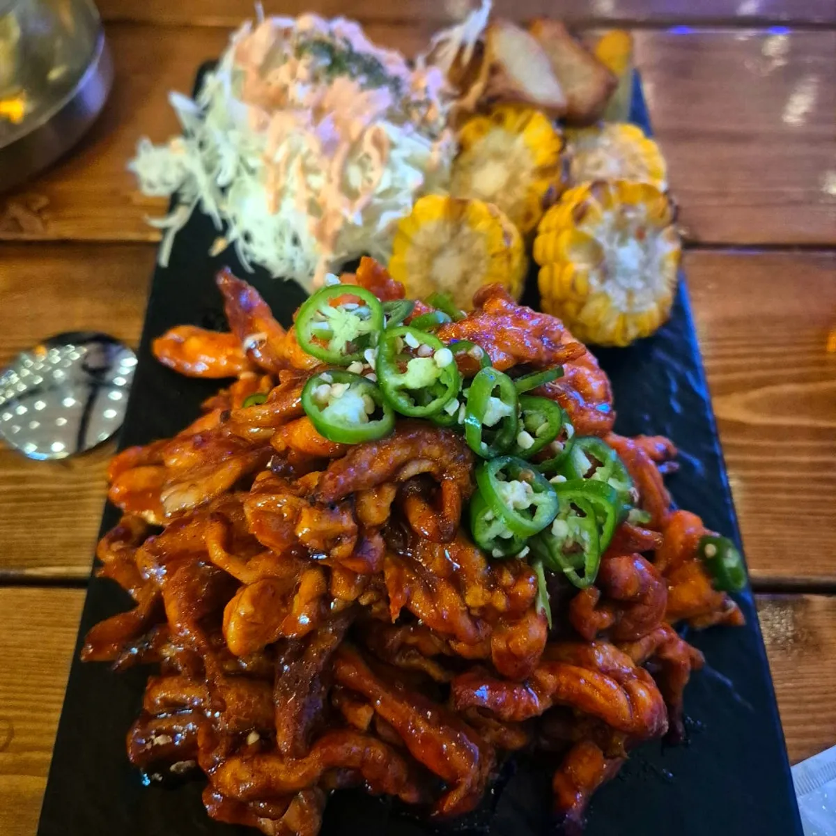 Signature charcoal-grilled chicken neck in sauce on a slate plate