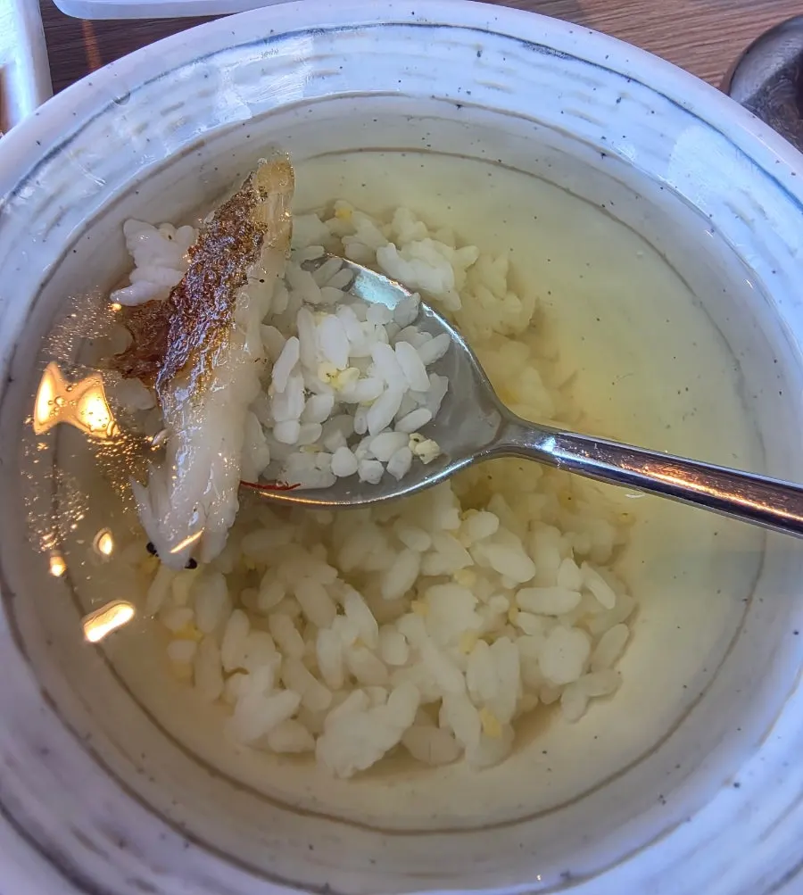 A bite of rice soaked in green tea water topped with dried corvina