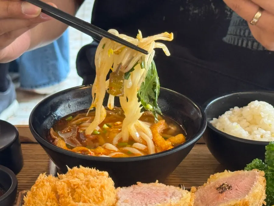 Spicy Hwa Udon topped with bean sprouts and crown daisy