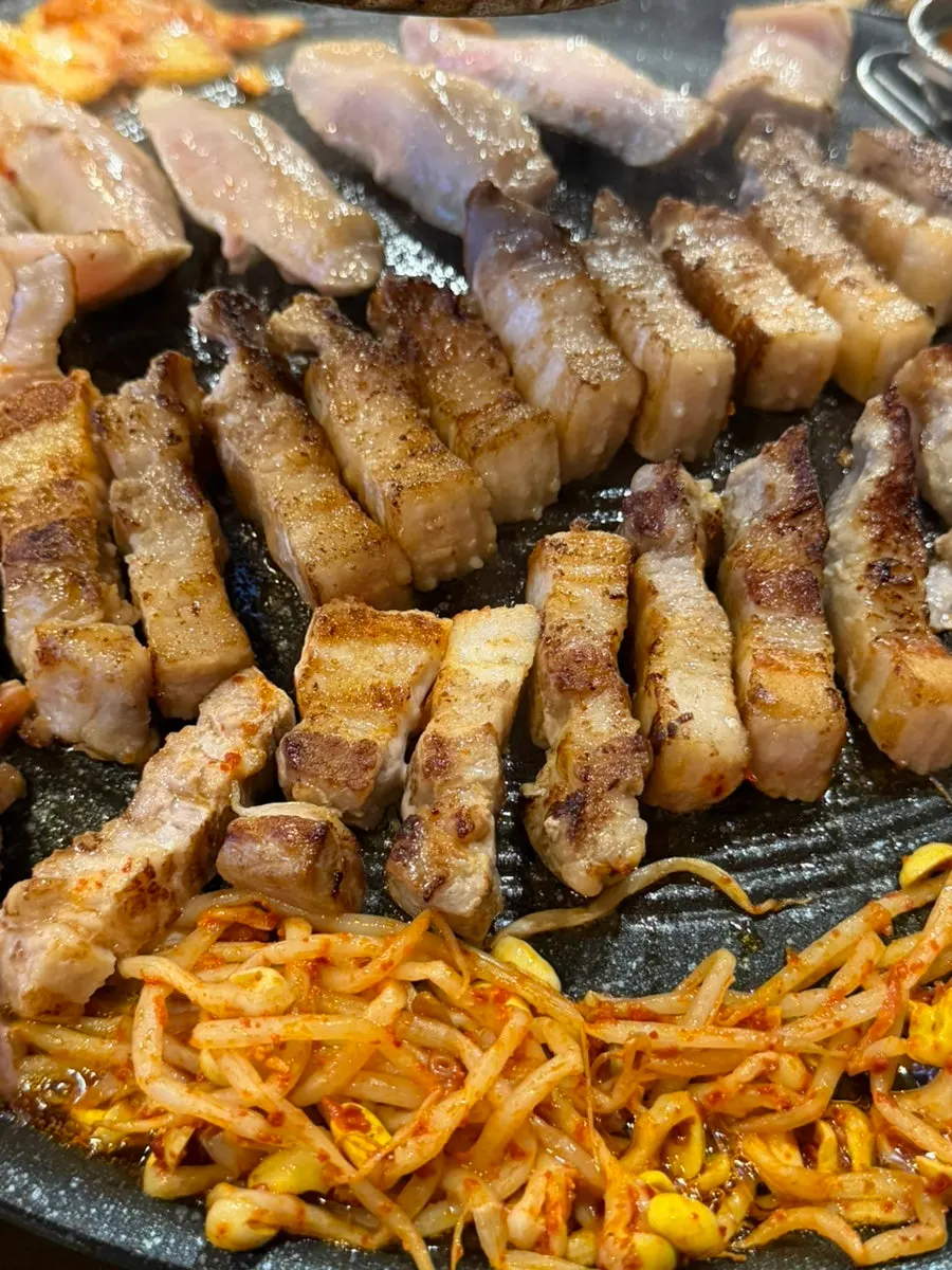 Pork belly cut with scissors alongside kimchi and bean sprouts