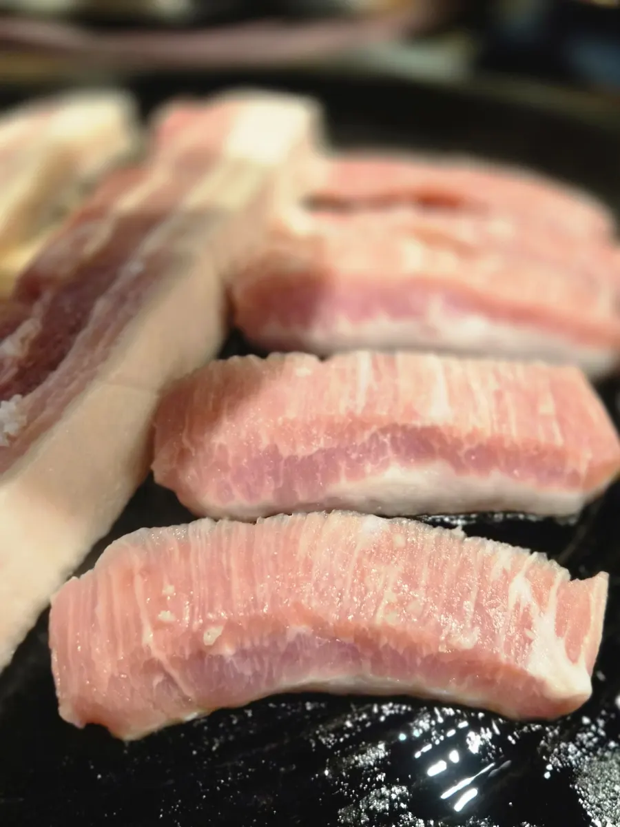 Pork belly and jowl laid on the cauldron-lid grill