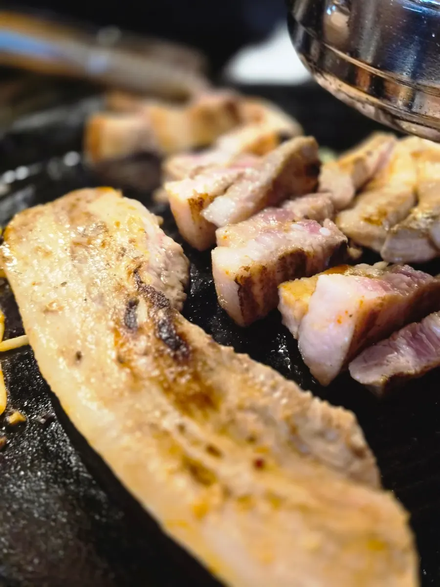Meat grilling on the cauldron lid