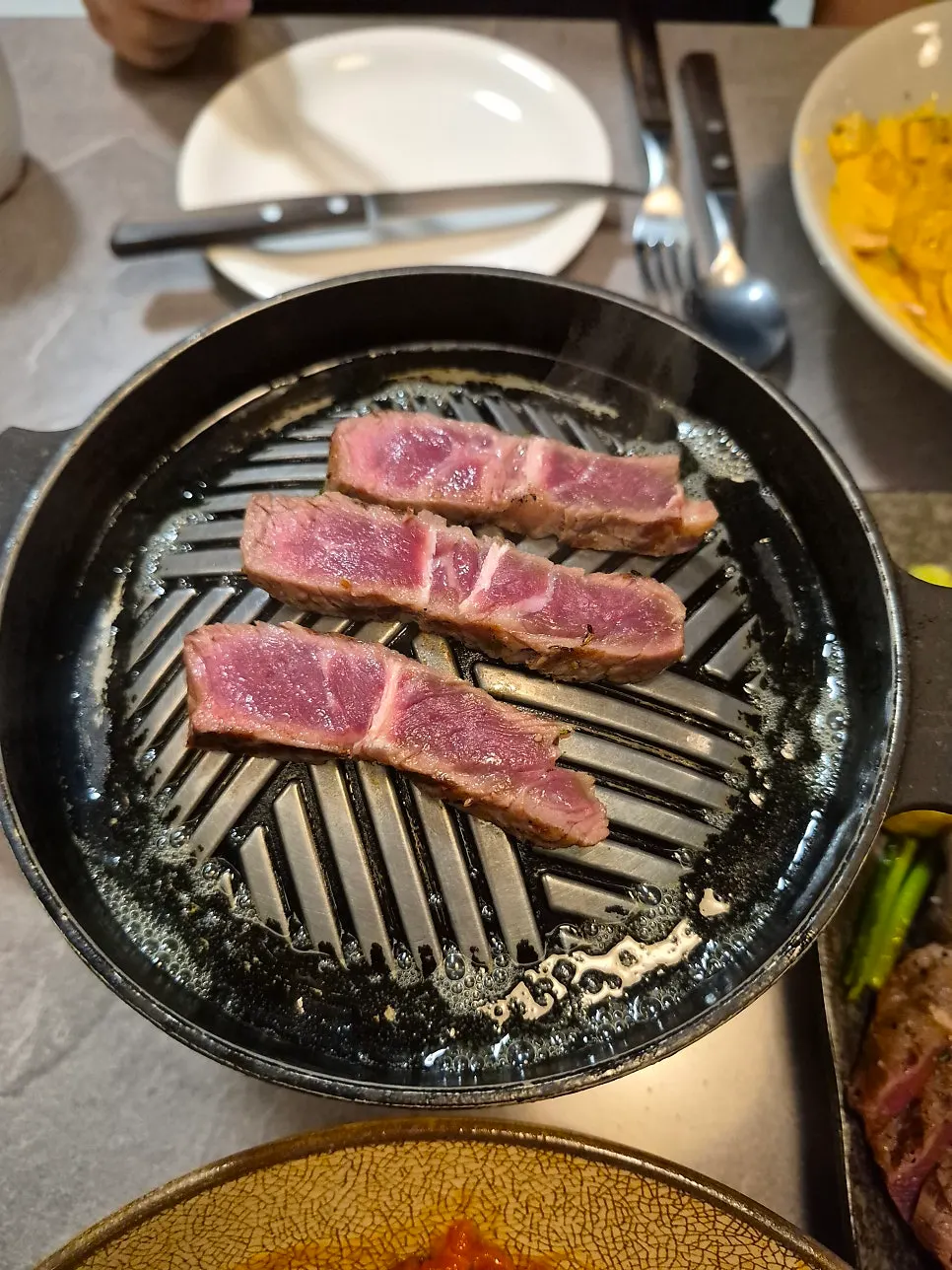 Chuck flap steak grilling with melted butter on the tabletop grill