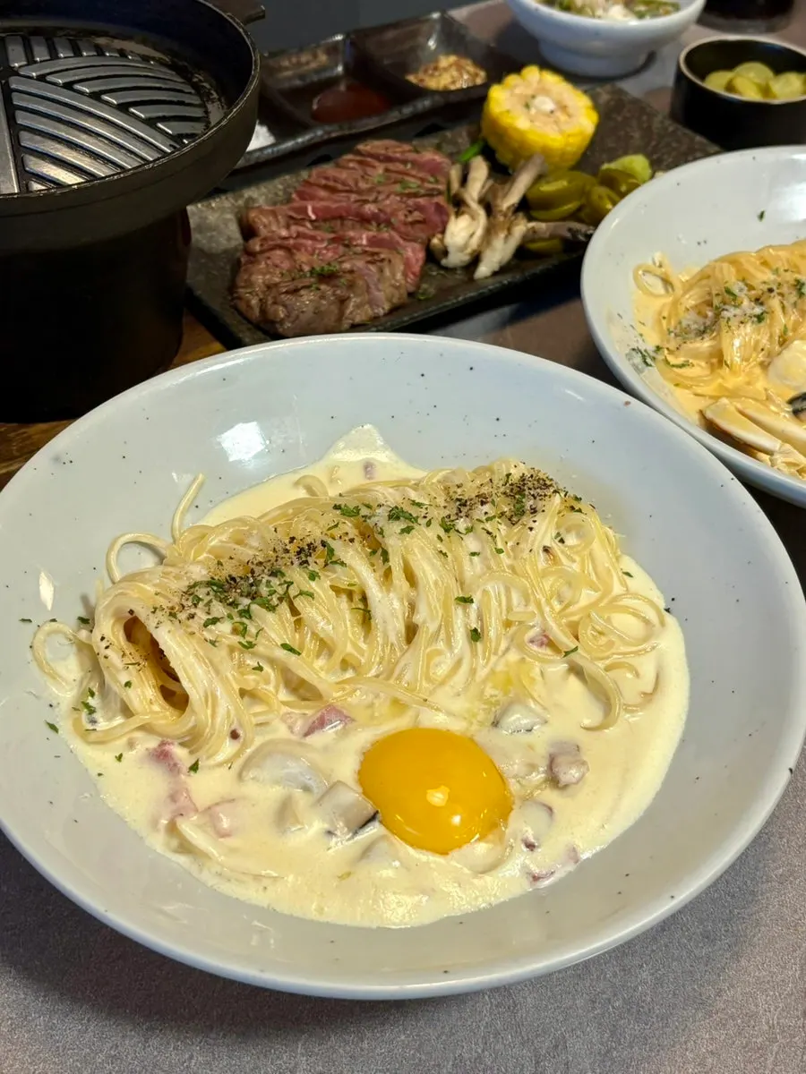 Full spread of two pasta plates and a steak