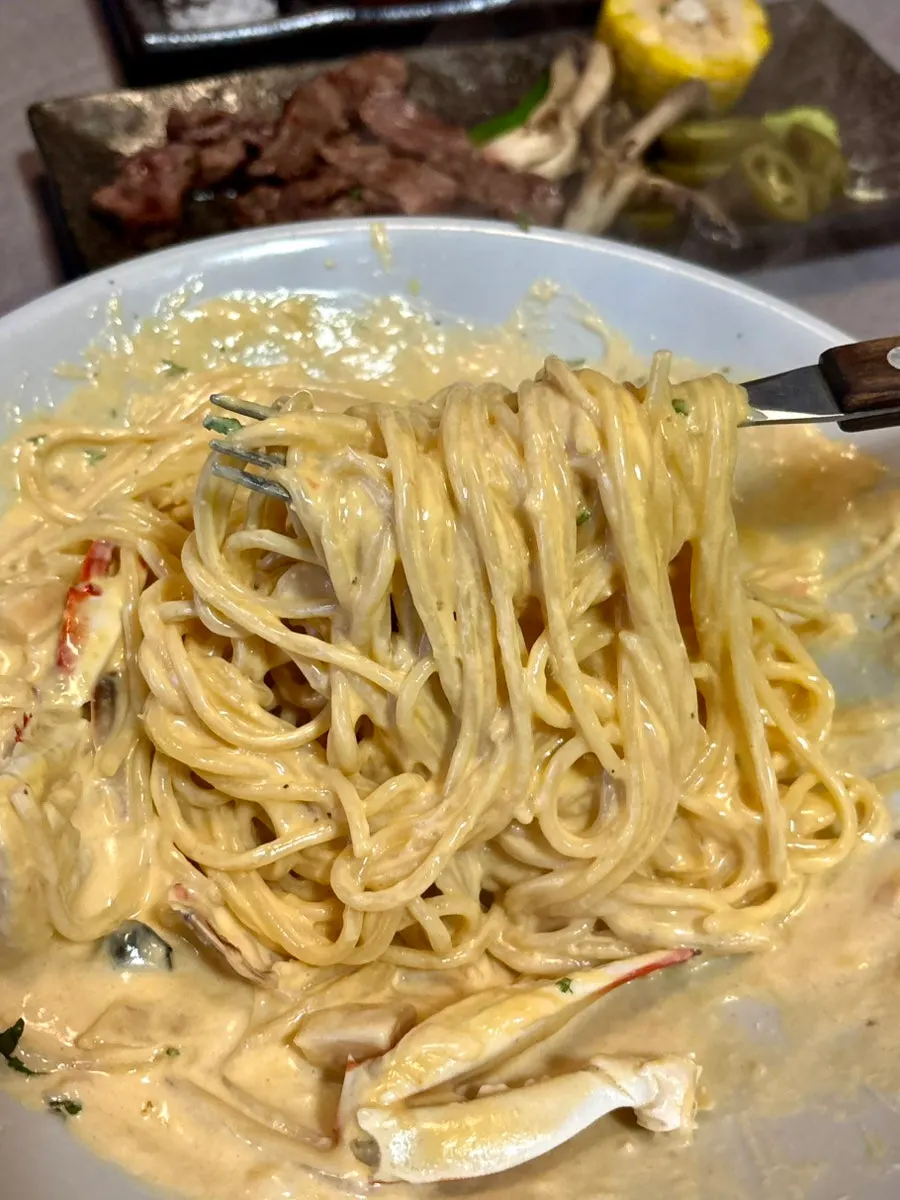 Lifting up a forkful of the spicy crab cream pasta