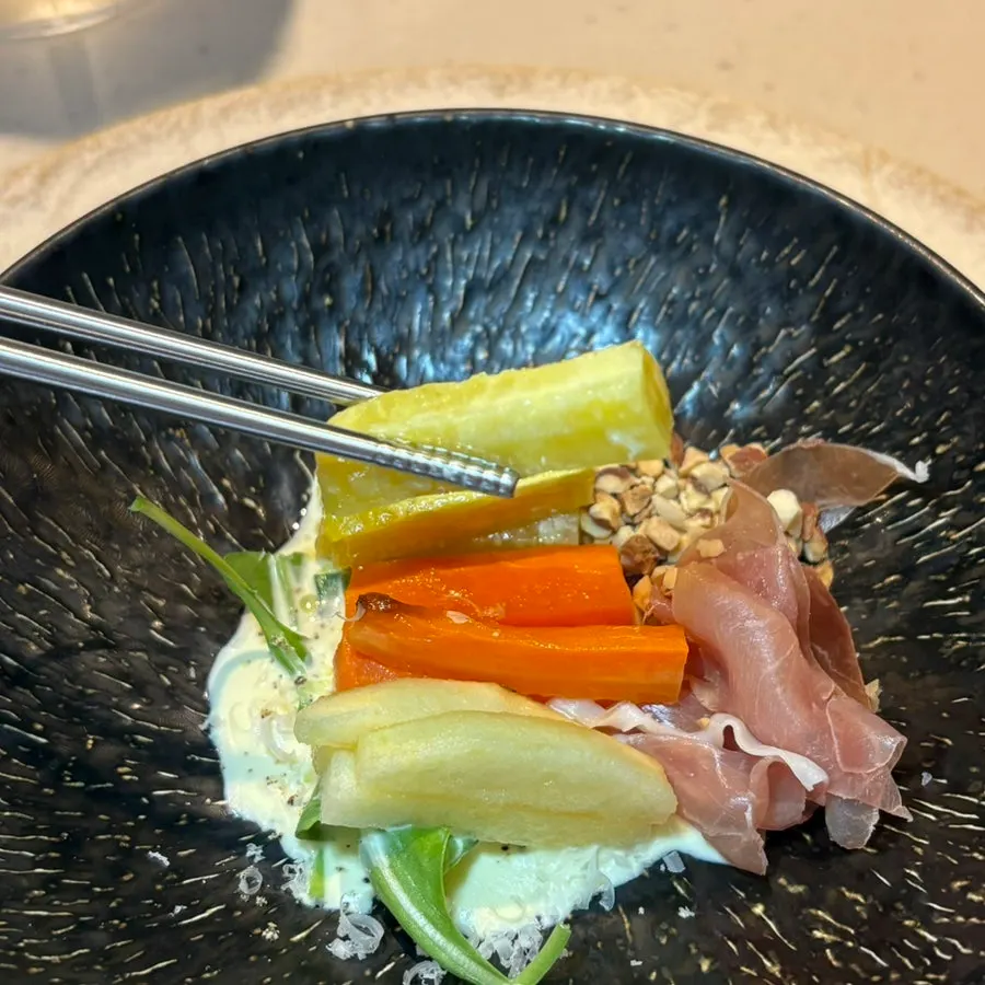 Grilled vegetable salad topped with almonds, zucchini, and prosciutto