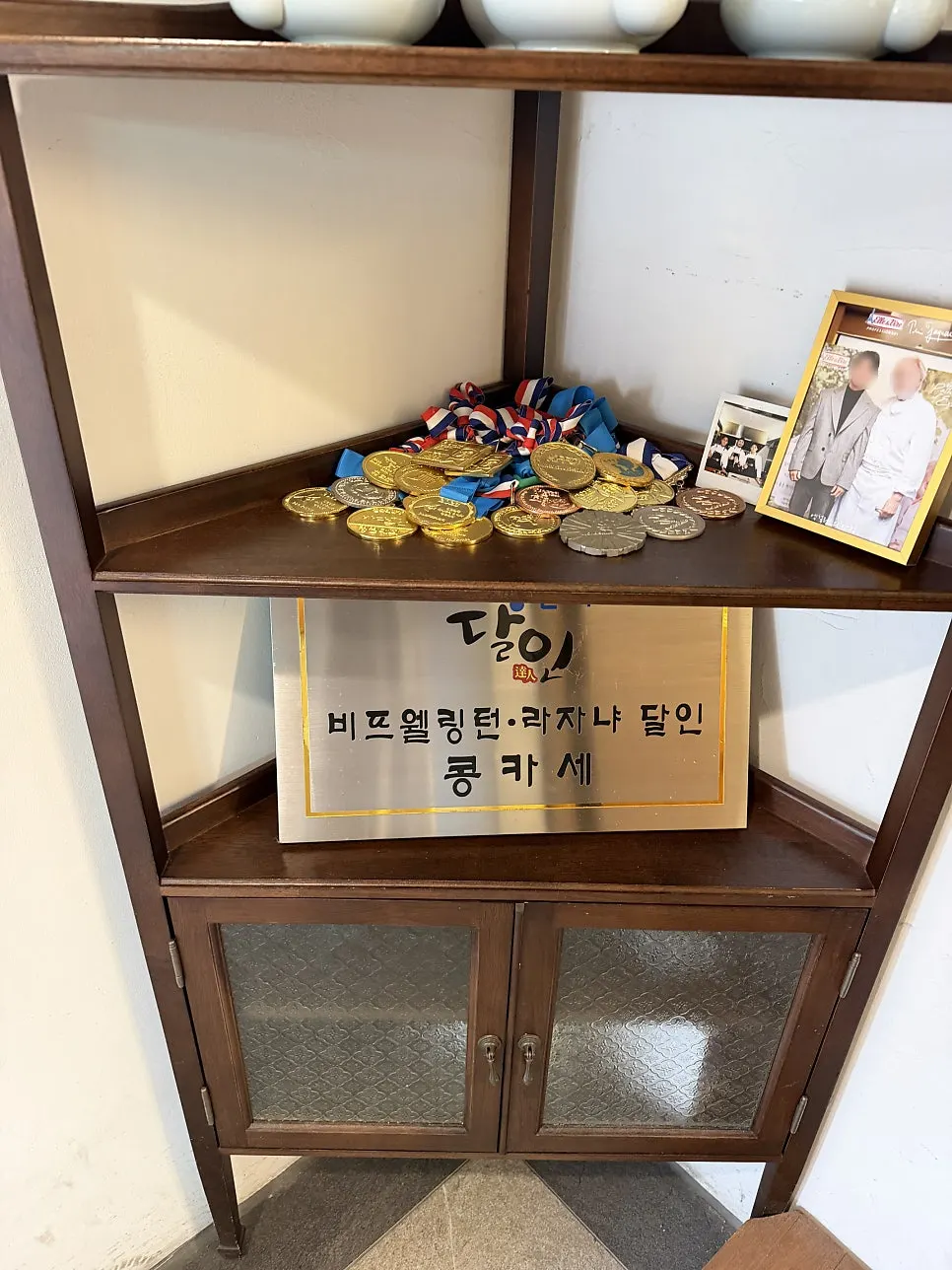 Corner display with the Master of Living plaque and cooking competition medals