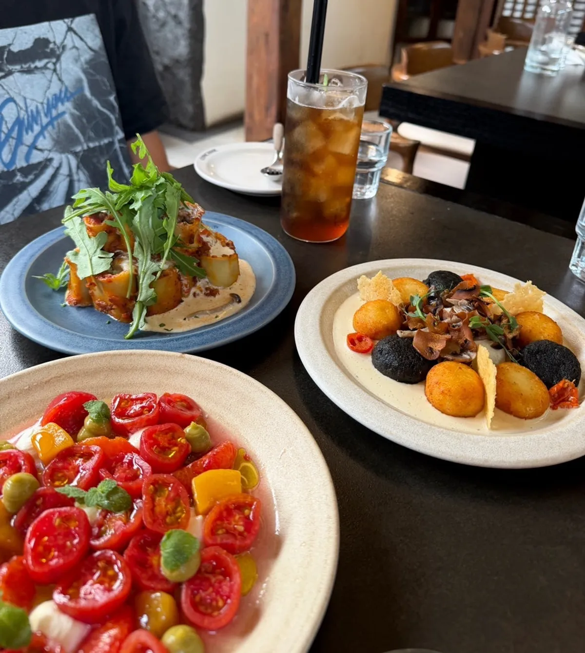 Table set with lasagna, gnocchi, and tomato salad
