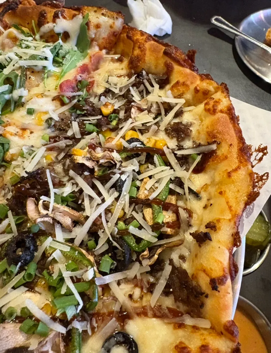 A slice of garlic shrimp pizza topped generously with rucola