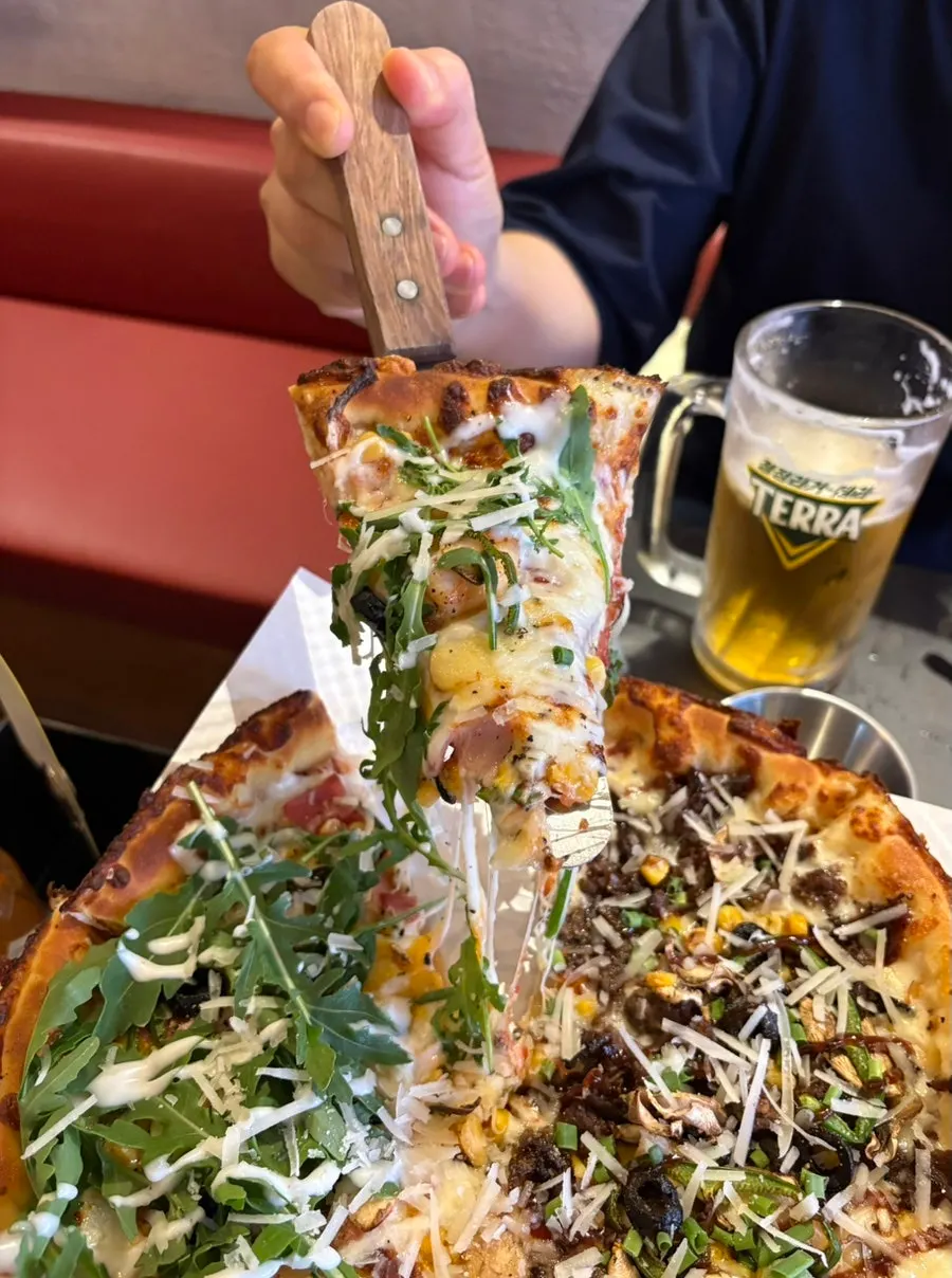 A whole pizza kept warm on the tabletop stove