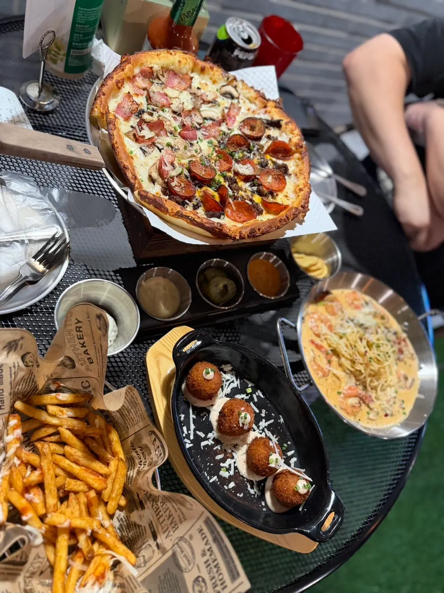 Table spread with pizza, pasta, and fries together