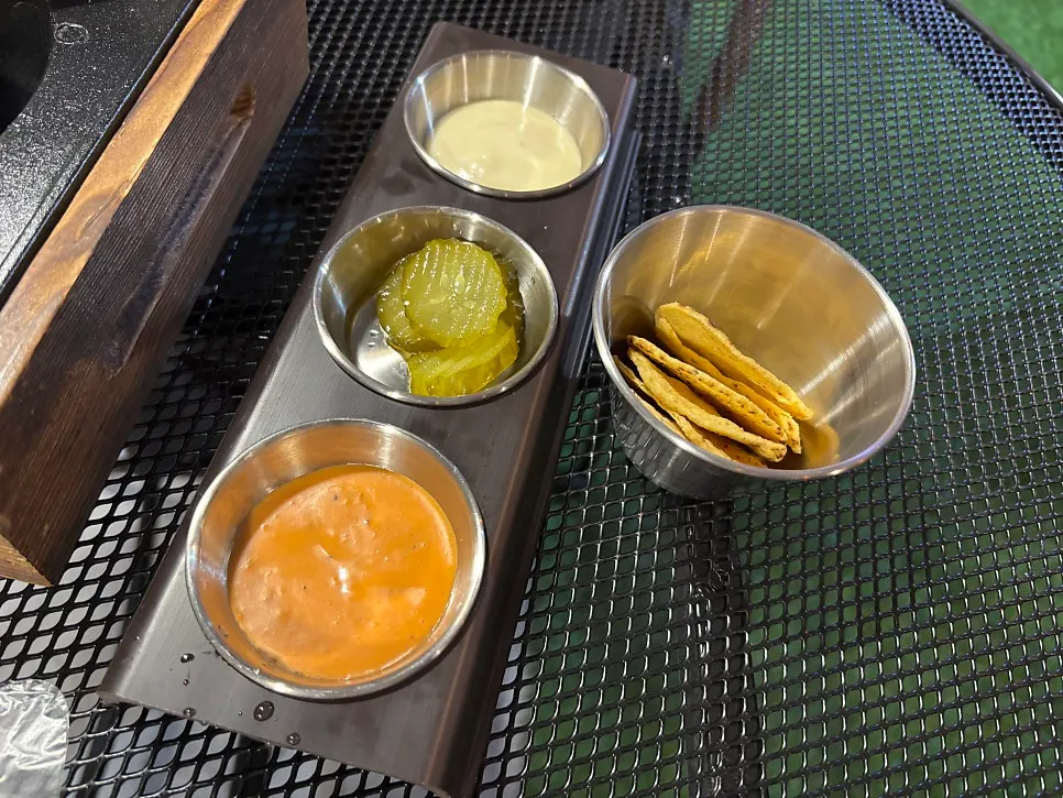 Basic side snack of nachos with pickles and dipping sauces