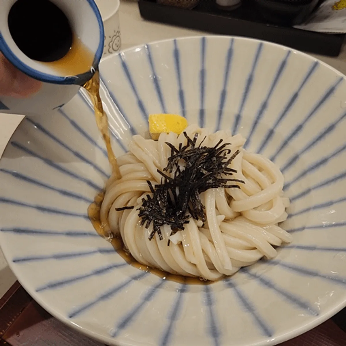 いなり寿司が添えられたコシ教大店のぶっかけうどん