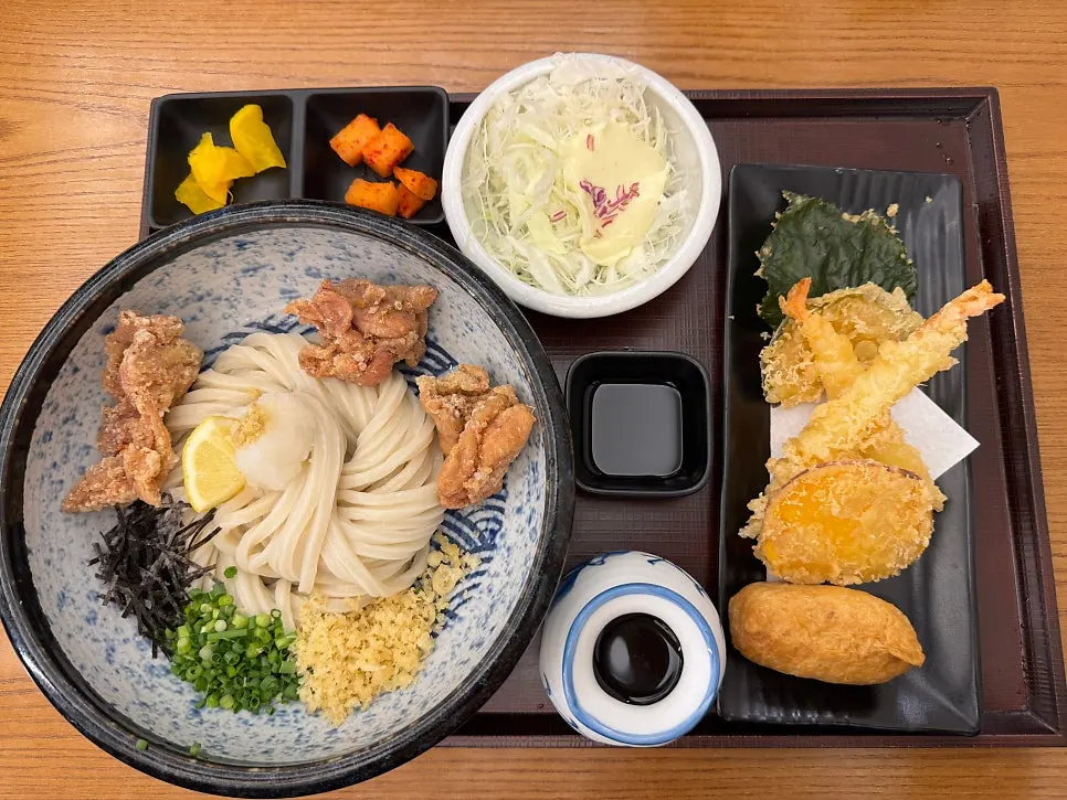 Udon set served with tempura, inari sushi, and side dishes
