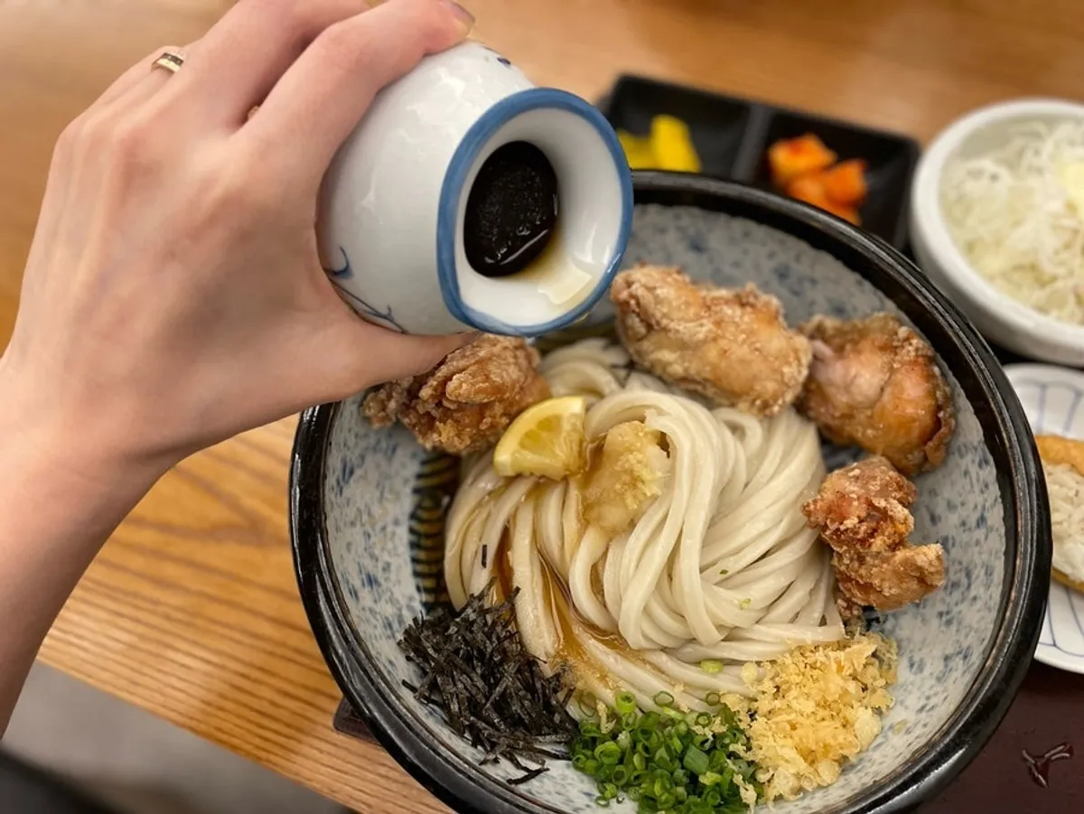 냉우동 면 위로 소스를 붓는 모습