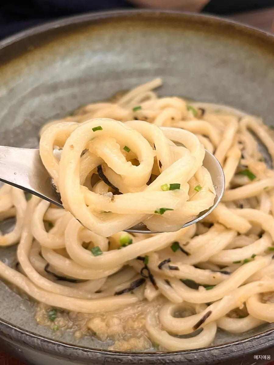 Tenbukkake udon mixed with tsuyu, lifted on a spoon