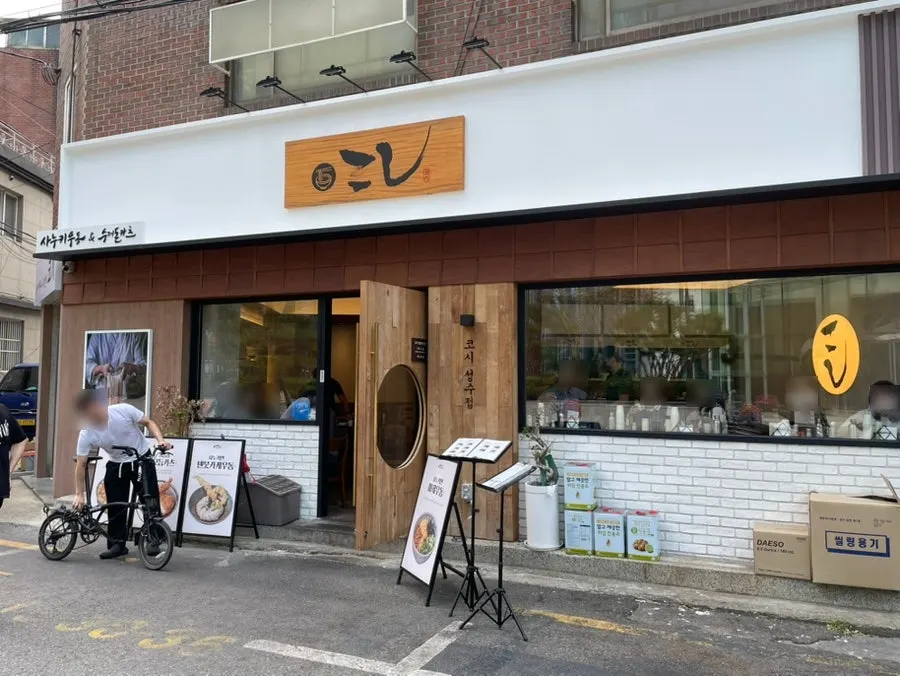 Entrance to Kosi Seongsu Branch with wood-toned exterior and wooden sign